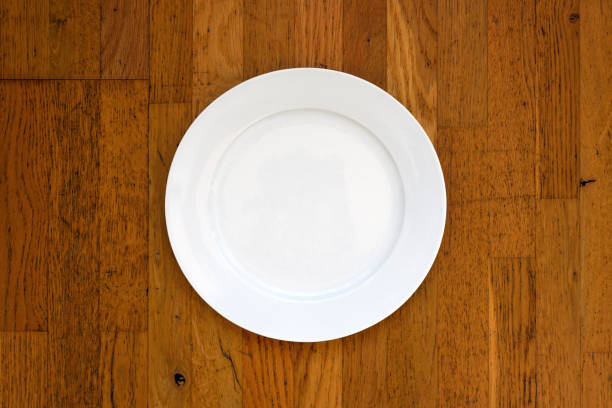 istock Empty white plate on wooden surface as mockup copy space, top view 1445205991