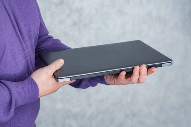 istock Man holds a laptop in his hands on a light background. 1445207168