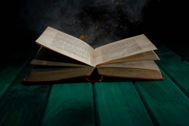 istock Old book on green table with smoke and sparkles - learning concept 1445207499