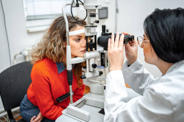 ophtalmologiste effectuant un examen de la vue avec un équipement optique sur une patiente - ophtalmologie photos et images de collection