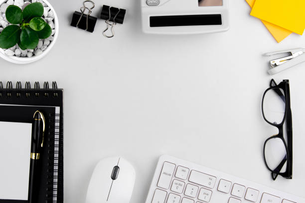 istock top view of modern white office desk with computer keyboard, blank notebook page and other equipment on white background. 1445209004