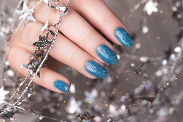 istock Hand with blue glitter nails with tinsel 1445211028