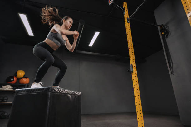 Female athlete doing box jump exercise at gym