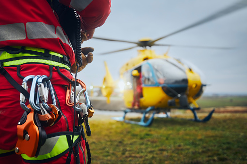 Selective focus on safety harness of paramedic of emergency service in front of helicopter. Themes rescue, help and hope.