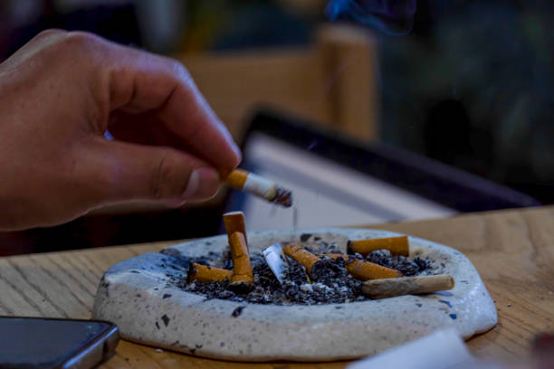 young man smoking on a wooden table, ashtray with several used cigars, mexico - cigar whisky bar cognac imagens e fotografias de stock