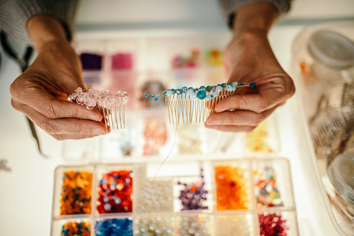 Woman has a small business manufacture workshop at home where she is making decorative elements and jewelry from wire and beads.