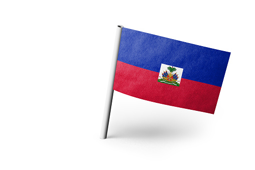 Small paper flag of Haiti pinned. Isolated on white background. Horizontal orientation. Close up photography. Copy space.
