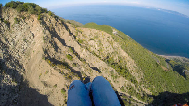 더러운 바다 위로 날아오르는 패러글라이딩 조종사. - skydiving base jumping extreme sports mountain 뉴스 사진 이미지