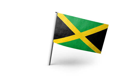 Small paper flag of Jamaica pinned. Isolated on white background. Horizontal orientation. Close up photography. Copy space.