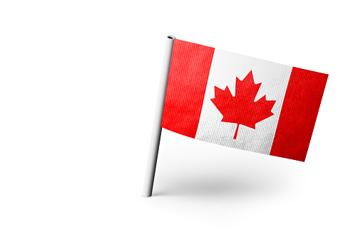 Small paper flag of Canada pinned. Isolated on white background. Horizontal orientation. Close up photography. Copy space.