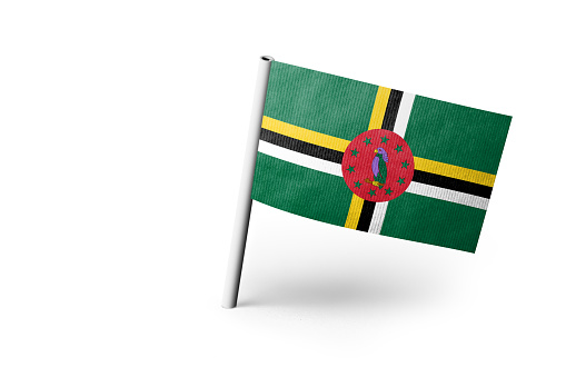 Small paper flag of Dominica pinned. Isolated on white background. Horizontal orientation. Close up photography. Copy space.