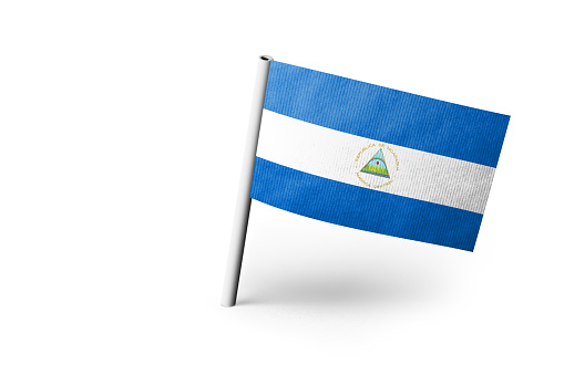 Small paper flag of Nicaragua pinned. Isolated on white background. Horizontal orientation. Close up photography. Copy space.