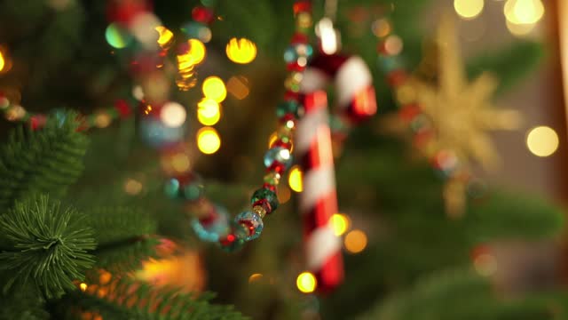 Christmas decoration cane lollipop on branch of Christmas tree on background of golden garland. New Year
