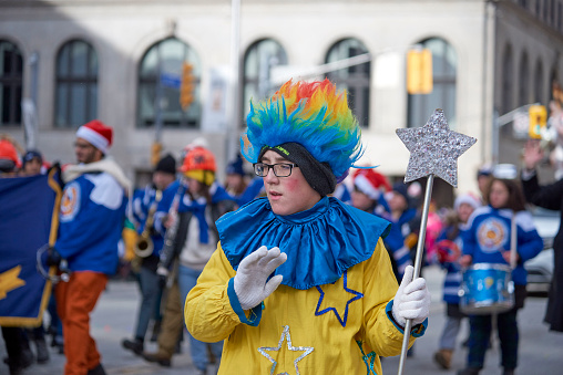 Toronto, Ontario, Canada- November 20th, 2022: A boy dressed in a parade outfit while holding a star on a stick is marching in Toronto’s annual Santa Claus Parade.
