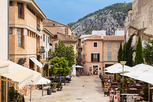 Pollença, Spain, July 20, 2018; Cozy little square with small shops and terraces in the charming mountainous village Pollença in the north of the Mediterranean island of Mallorca in Spain.