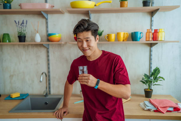 istock Young man drinking water at home 1445218423
