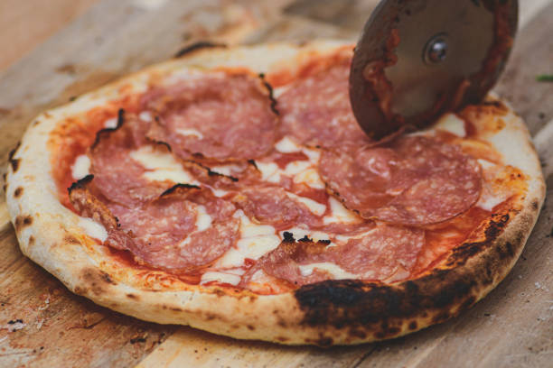 istock Cutting hot pizza with tomato sauce, mozzarella and salami meat 1445218567