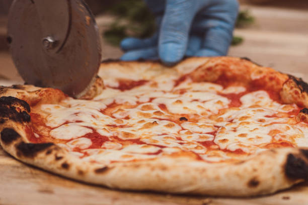 hand mit plastikhandschuh schneiden heiße pizza margherita mit tomatensauce und mozzarella - pizza pastry crust oven meat stock-fotos und bilder