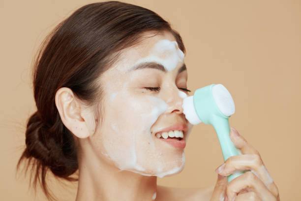 istock young woman with massager washing face 1445219890
