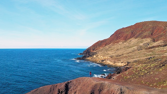 Aerial view of a hiker looking to the volcanic cone of Montaña Roja in El Medano, Tenerife Islands