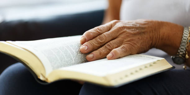 primer plano de las manos de una mujer mayor en la biblia, dobladas en oración - senior women caucasian one person religion fotografías e imágenes de stock