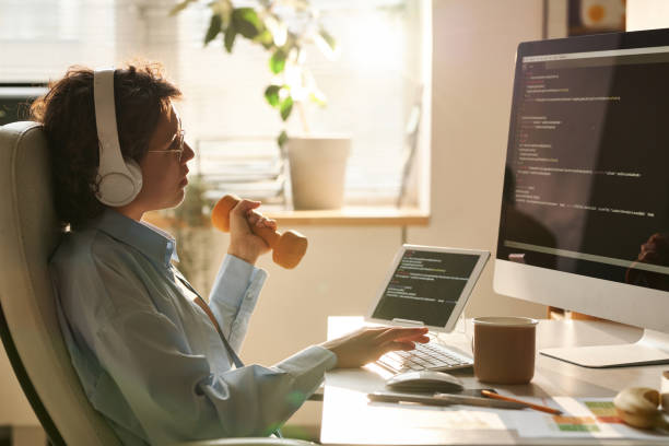 istock Female programmer exercising with dumbbells at her workplace 1445225779