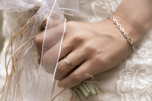 bride with a modern gold bracelet, wedding ring and solitaire ring on her wrist, holding elegant modern autumn wedding bouquet. The concept of lifestyle and autumn wedding