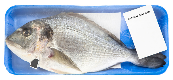 Fresh gilthead bream fish inside a plastic tray with cellophane cover packaging