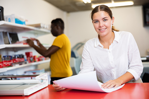 Portrait of an attentive woman checking quality of printing in a printing house