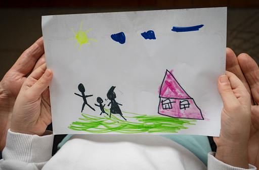Child and her grandfather holding a drawn house with family