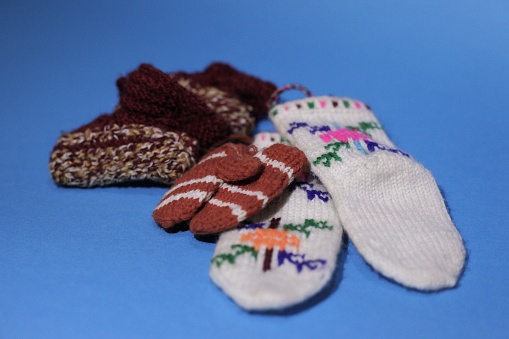 knitted gloves, socks and sneakers of various colors on a blue background