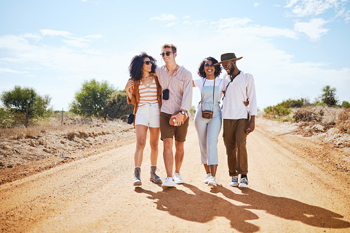Travel, adventure and friends walk on road path together to explore the Arizona desert in the USA. Bush holiday adventure with diverse friendship and couple group enjoying summer sunshine break.