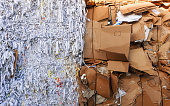 stack of shredded waste paper and cardboard in front of a recycling facility