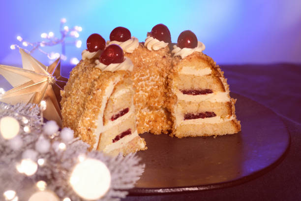 istock German cake Frankfurter Kranz or Frankfurt Crown Cake. Bisquit with butter cream and cherry. Cut half of the cake on black plate. Dark blue background.Xmas fir twigs, paper star, garland. 1445242554