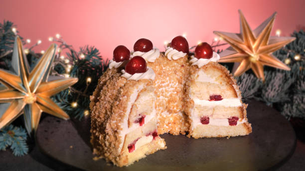 istock German cake Frankfurter Kranz or Frankfurt Crown Cake. Bisquit with butter cream, cherry. Half of the cake on black plate. Black and pink background.Xmas fir twigs, star, garland with lights. 1445242556