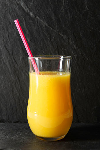 Fresh orange juice and oranges on wooden table.