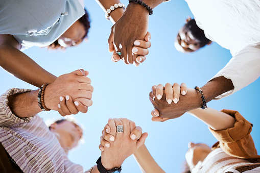 Diversity, people and hands in support, trust and unity for community against sky background. Diverse group hand holding together in united team building collaboration and teamwork solidarity success