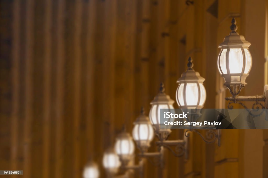 lights on the front of the building a row of old luminous lanterns on the facade of a building in the evening Abstract Stock Photo