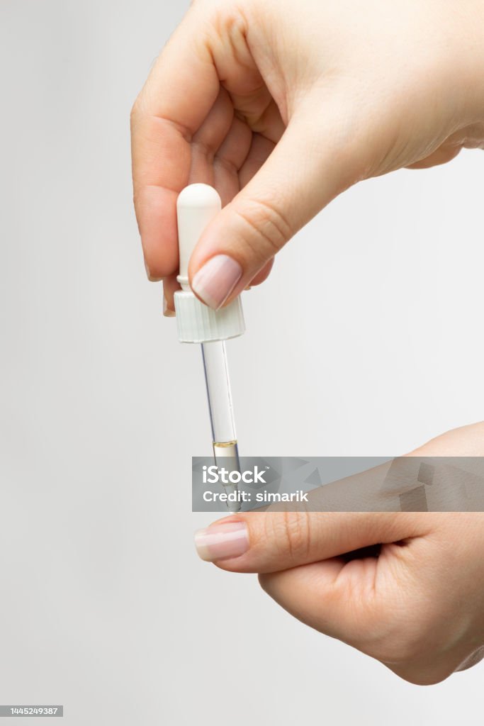 Nail Care Hand nail is about to receive a drop of nail care serum in front of white background. Applying Stock Photo