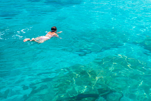 Happy woman swimming in the clear sea.