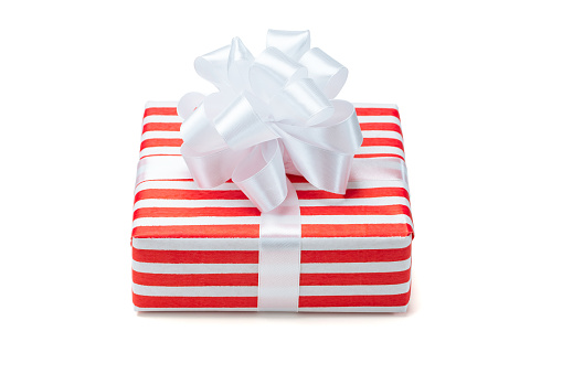 Close up shot of present box wrapped in red and white striped paper and decorated with a bow, isolated on white background.