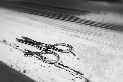 Beautiful scissors for cutting leather on a production metal table. Grainy film style with circular motion blur effect.