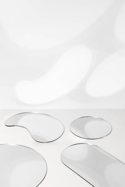 istock Small mirrors of different geometric shapes on the table, reflecting light on a white wall. 1445254312