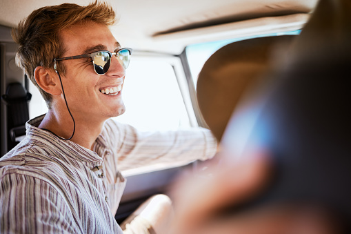 Road trip, friends and man relax in a car, bonding with driver in the passenger seat. Freedom, summer and adventure with smiling man enjoying vacation and drive in city, laughing, joking and cheerful