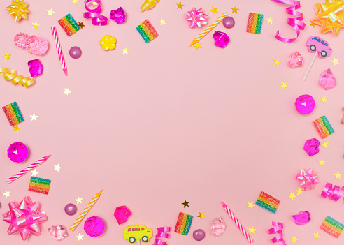 Children birthday party background with candles sweets crystals ribbons and confetti over pink background.