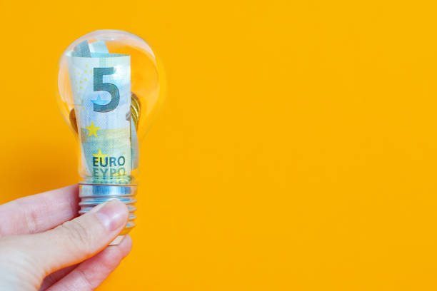 istock Banknotes and coins inside a light bulb on yellow 1445259511