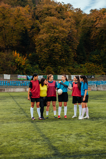 A group of young Caucasian soccer girls are in the field standing and talking together ready to start the practice.