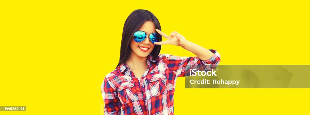 Portrait of beautiful happy smiling young brunette woman in sunglasses on yellow background 18-19 Years Stock Photo