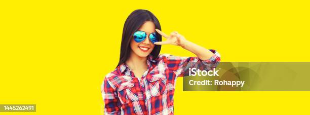Portrait Of Beautiful Happy Smiling Young Brunette Woman In Sunglasses On Yellow Background Stock Photo - Download Image Now
