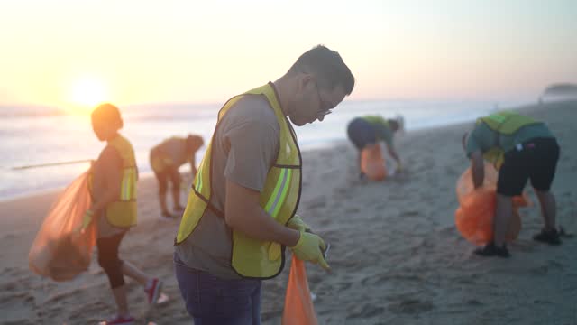 Young volunteer man picking up trash on a beach